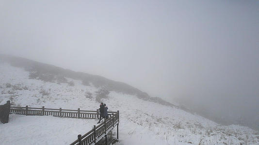 航拍冬天在山顶观景台上欣赏雪景的情侣4k素材视频的预览图