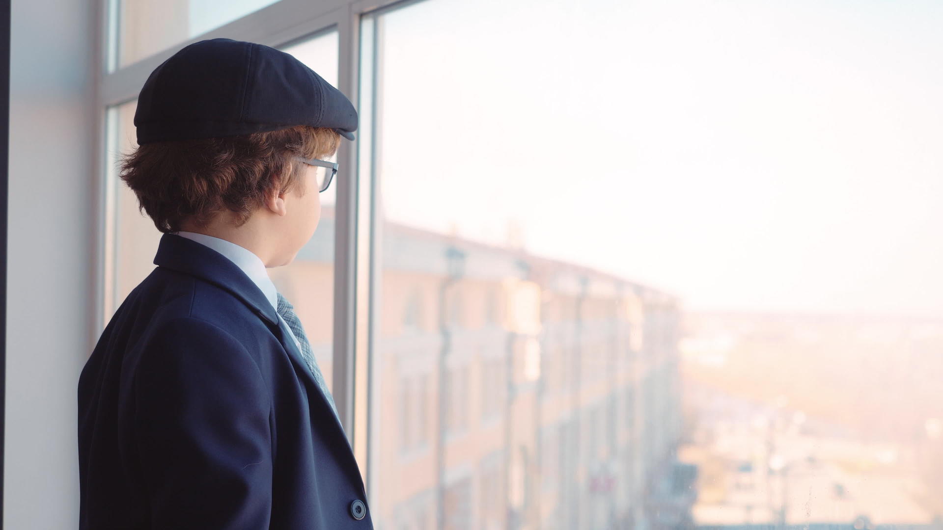 商务办公室窗口穿着商务西装、领带和帽子的年轻男孩视频的预览图