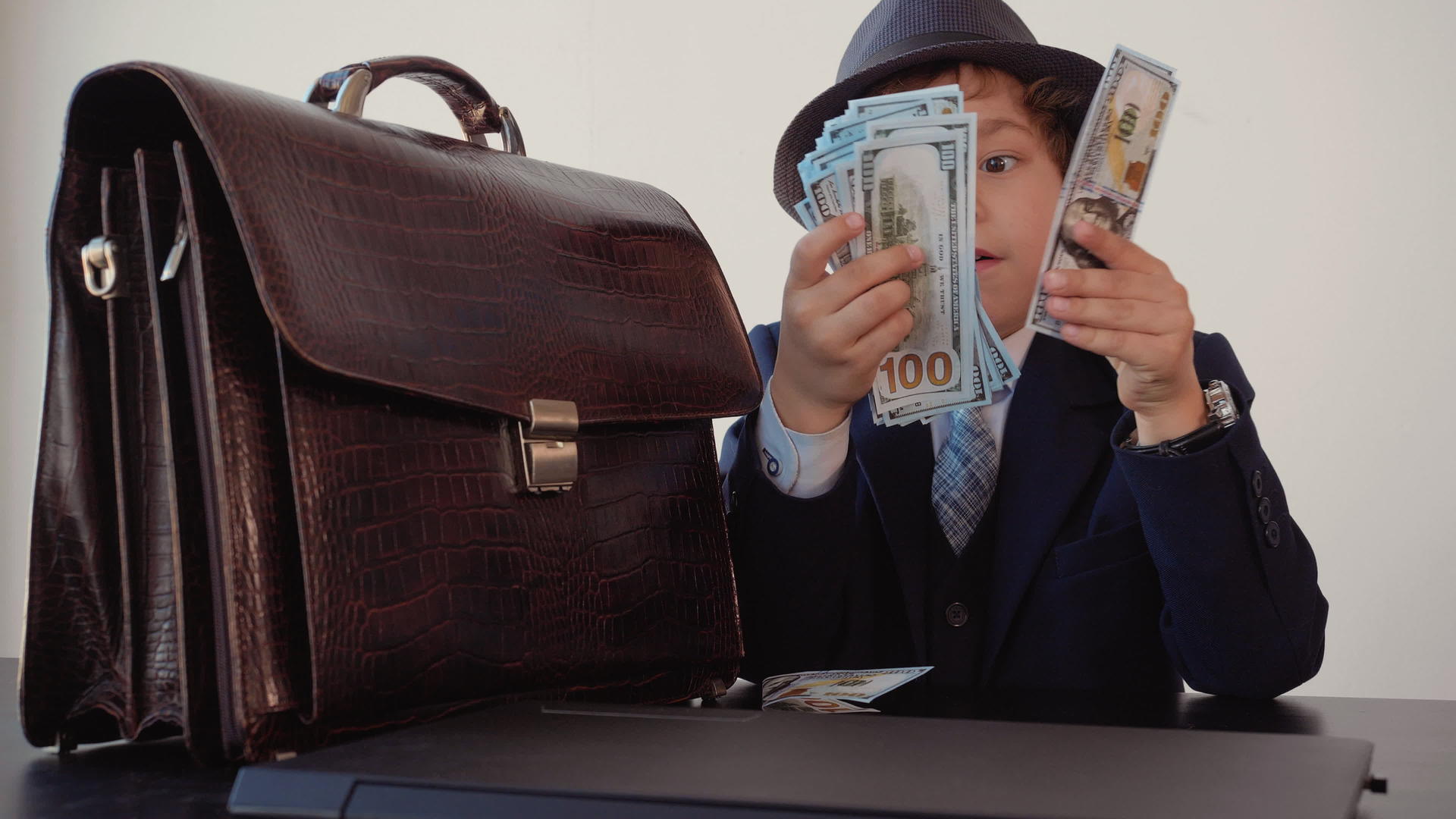 年轻的男孩和商人手里拿着钱堆在办公室里视频的预览图