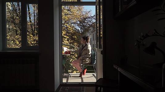 在阳光明媚的秋天年轻的白人妇女在露天阳台上准备茶杯视频的预览图
