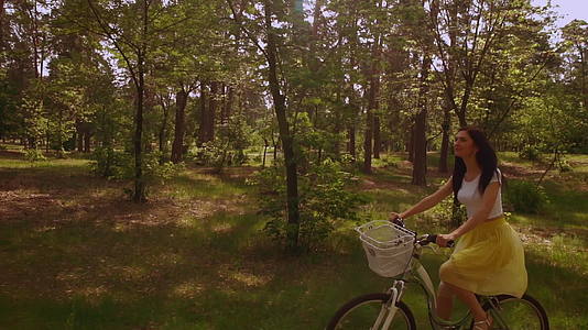 一个微笑的女孩在自行车阳光下骑自行车视频的预览图