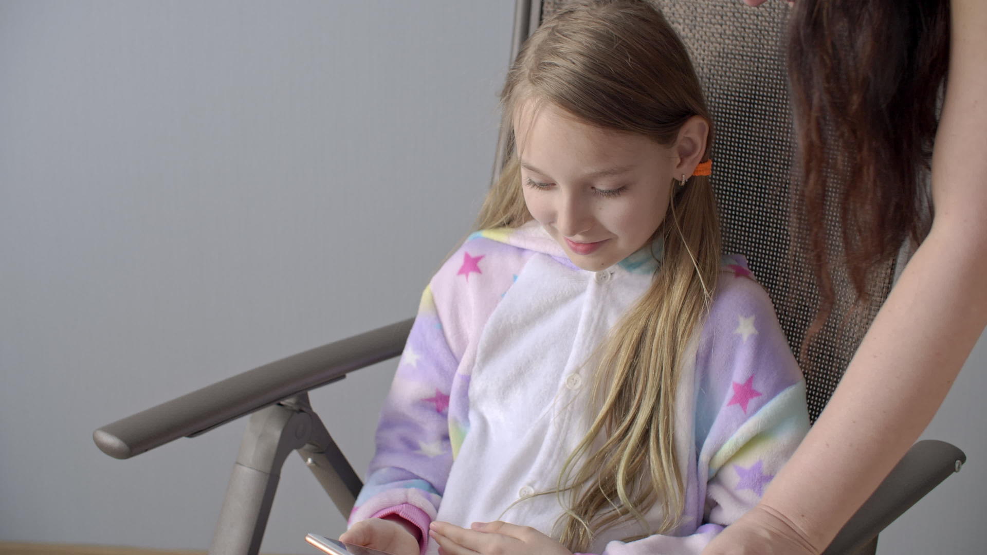 微笑的女孩用手机在椅子上看社交网络快乐的女儿和青少年视频的预览图