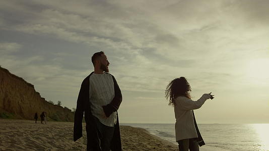 调皮的夫妇走在沙滩上日落海天视频的预览图