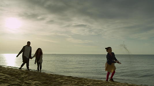 可爱的人走在岸边的夕阳沙滩上视频的预览图