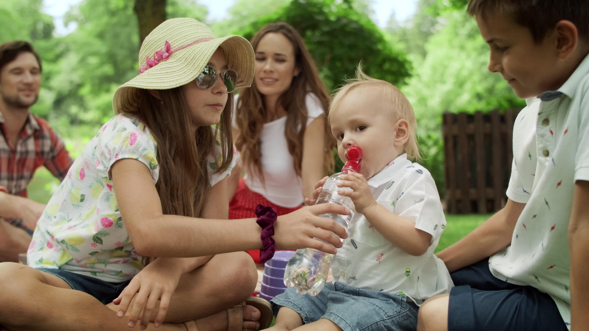 一家人坐在公园的毯子上一个可爱的孩子由瓶装饮用水制成视频的预览图