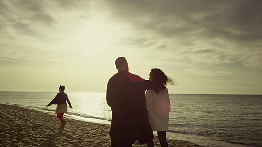 一家人在夕阳的天空中自然放松走在沙滩上视频的预览图