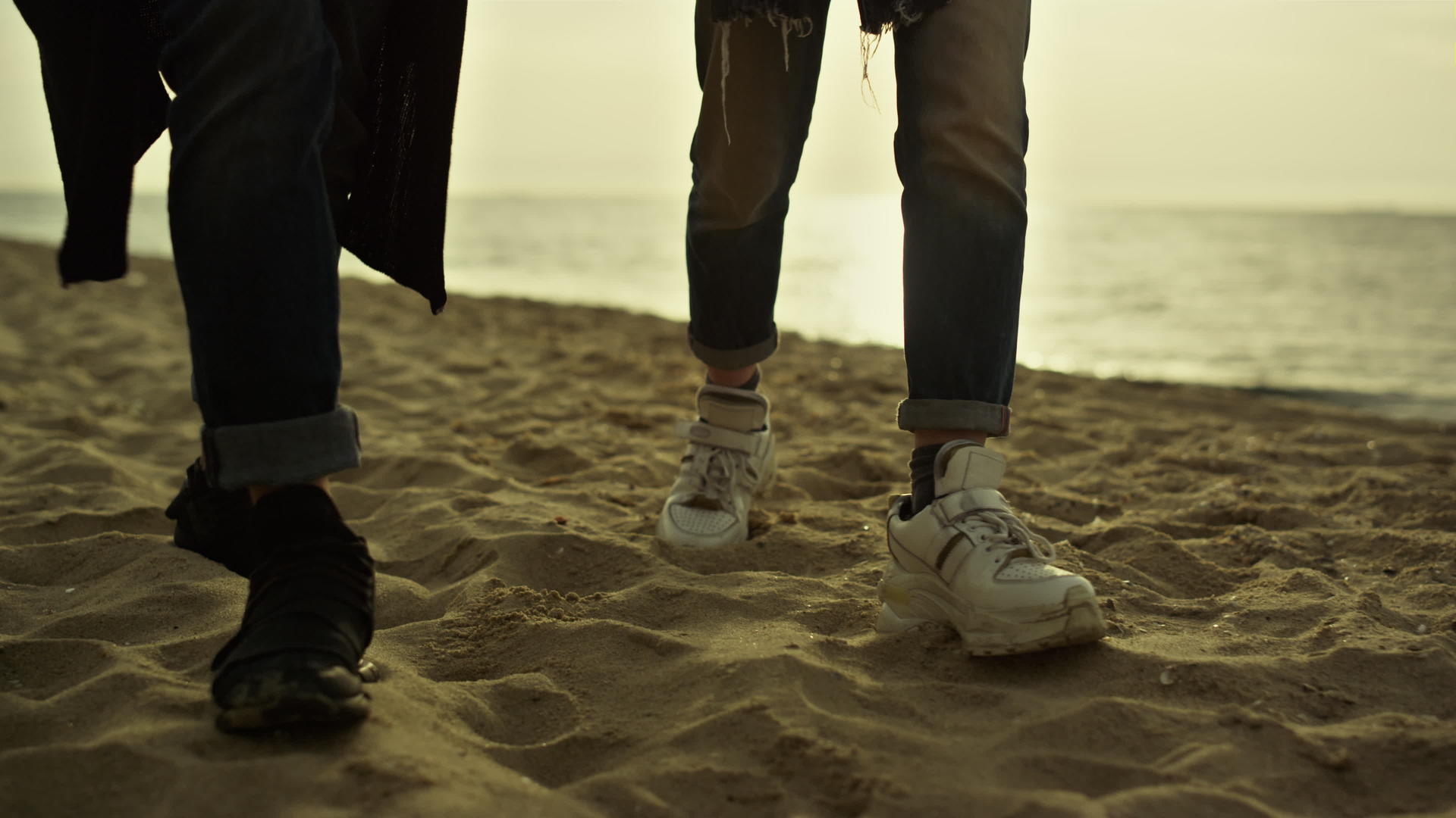 日落海上度假时人们双腿走在沙滩上视频的预览图