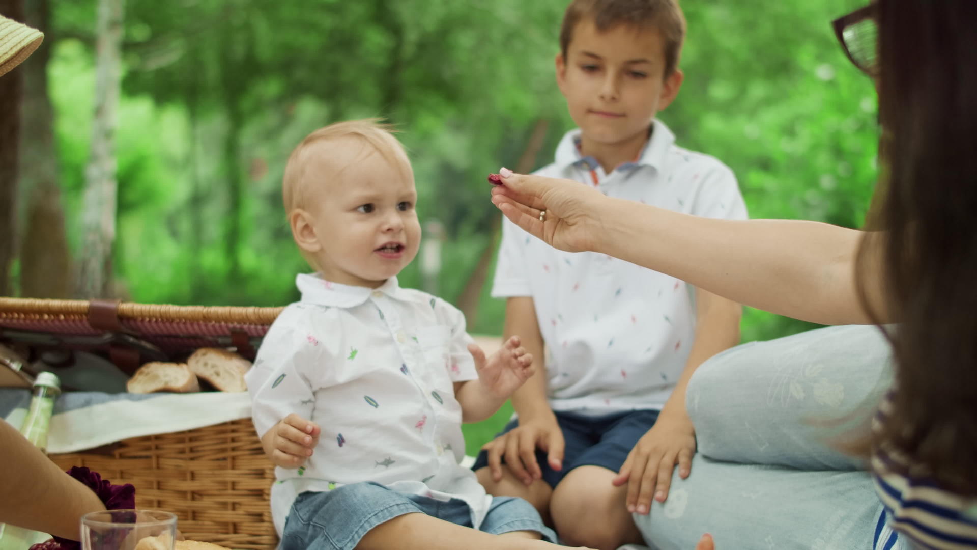 母亲在公园里喂小儿子吃樱桃视频的预览图