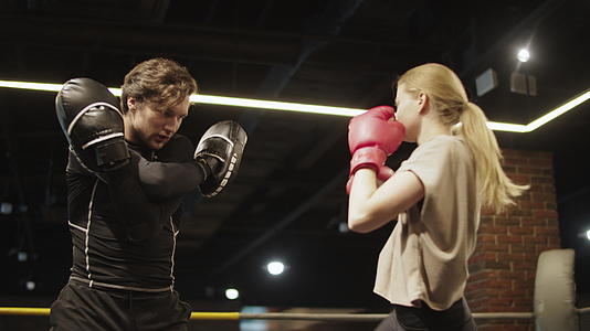 在拳击场与教练一起训练友好的健身女孩视频的预览图