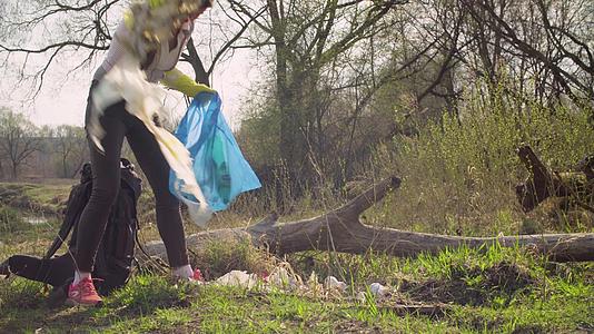 绿色女性活动人士在森林中收集垃圾视频的预览图