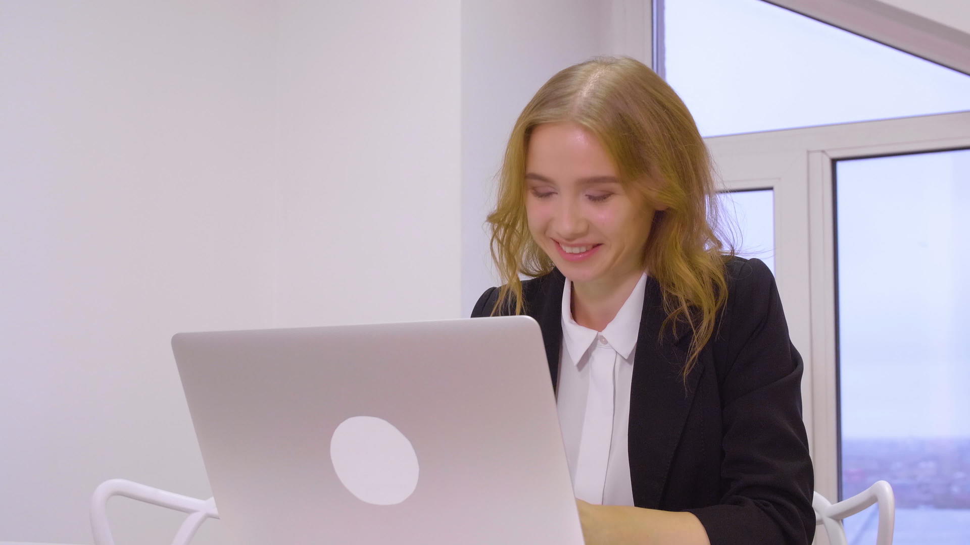 快乐的商业女性在商业办公室工作时使用膝盖电脑视频的预览图