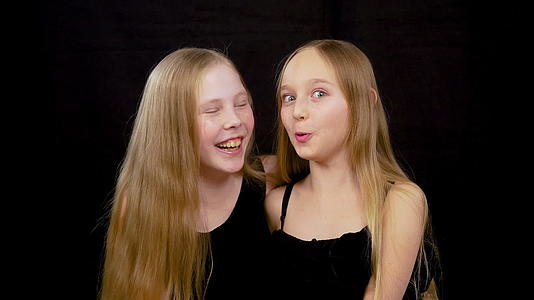 两个快乐的女孩玩得很开心在黑暗的工作室里打扮成黑色的背景视频的预览图