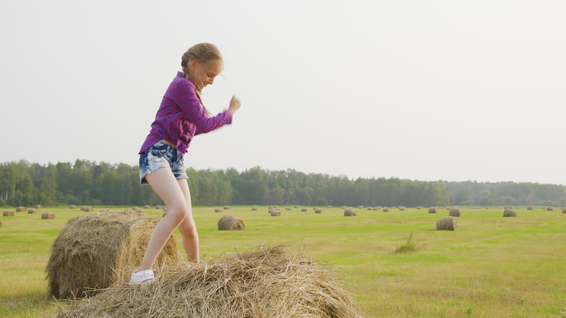 快乐的女孩在收割场的干草堆上跳舞视频的预览图