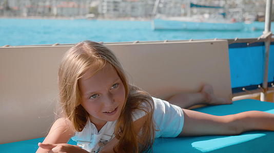 快乐的女孩躺在海上巡航的帆船上年轻的女孩在海上散步视频的预览图