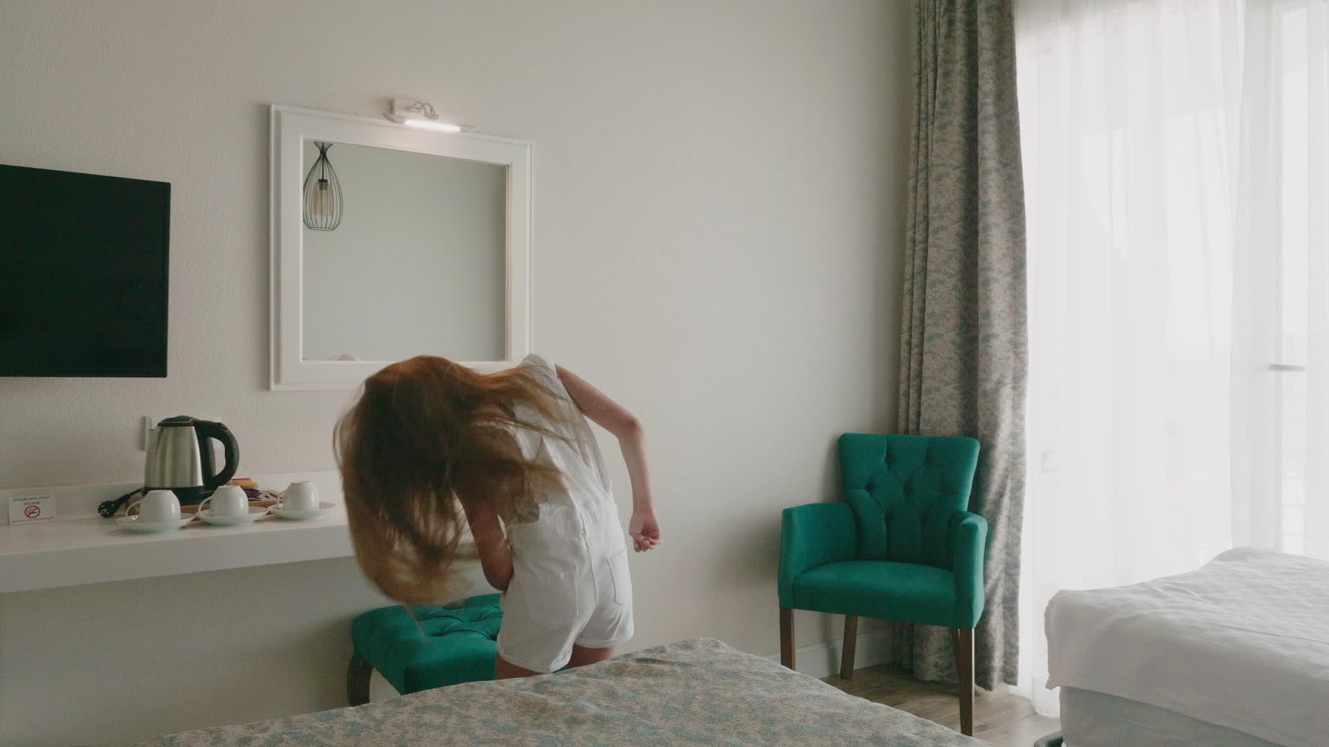 快乐的女孩在度假酒店的卧室里跳舞视频的预览图