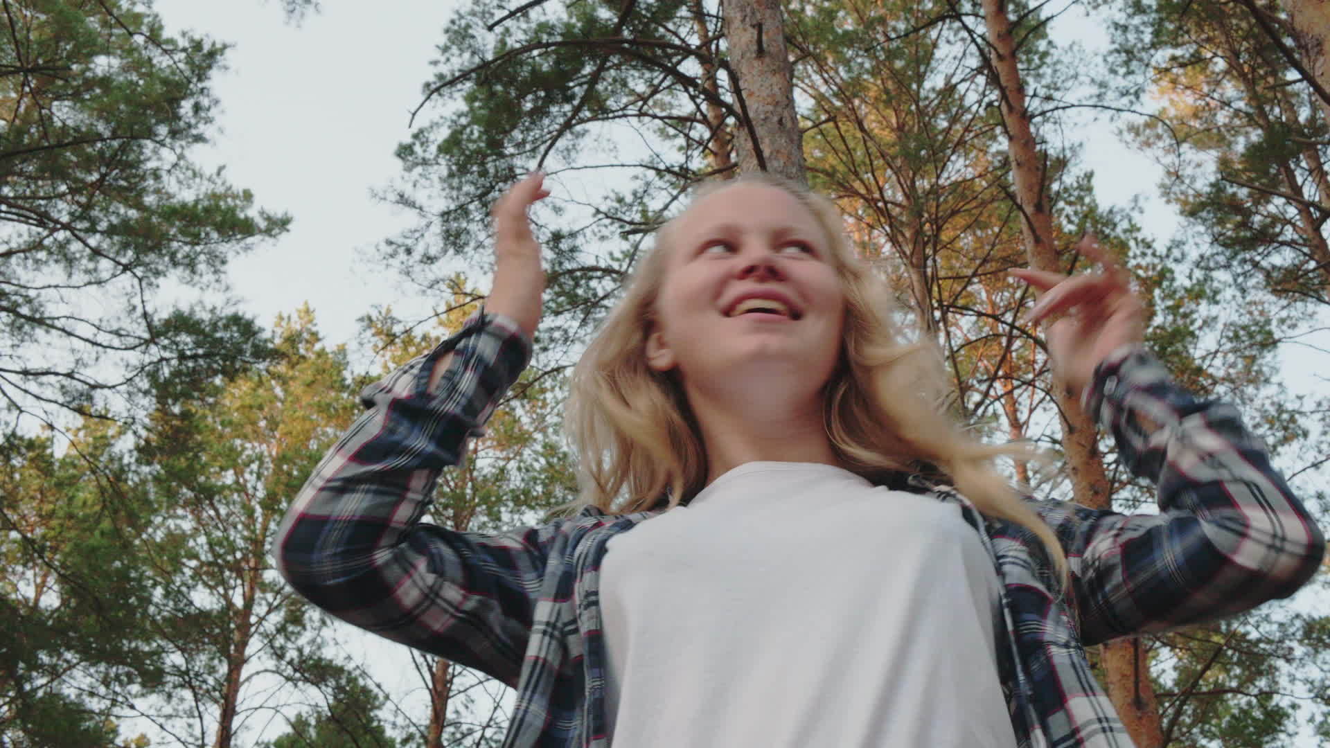 在松林中快乐的女孩与她的头和手一起跳舞在松林中微笑的女孩视频的预览图