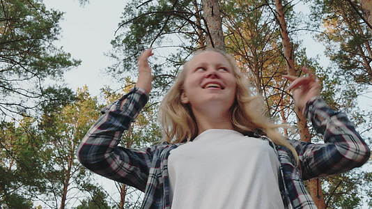 在松林中快乐的女孩与她的头和手一起跳舞在松林中微笑的女孩视频的预览图