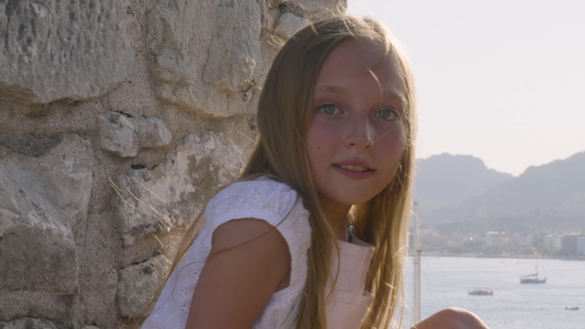快乐的女孩石墙上的少年肖像美丽的女孩在山海中视频的预览图