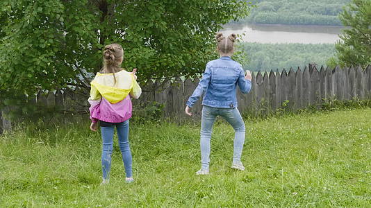两个快乐的女孩在草坪后院跳舞视频的预览图