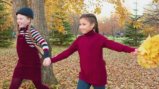 快乐的女孩们在美丽的秋天公园里一起奔跑视频的预览图