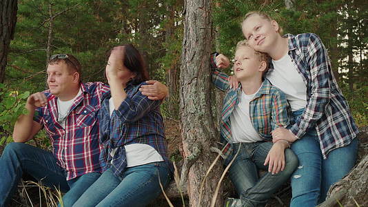 暑假期间幸福的家庭在针叶林中拥抱母亲、儿子、父亲和女儿视频的预览图
