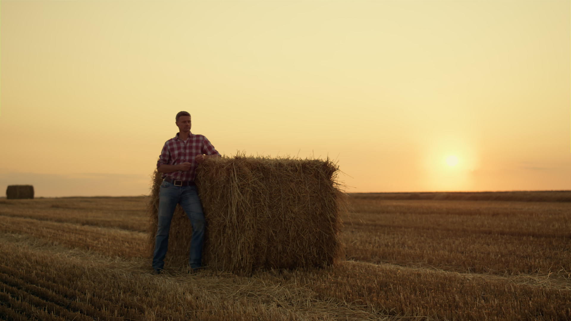 农民们独自站在黄金夕阳下的干草堆里视频的预览图