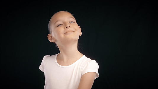 一个穿着白色裙子的快乐女孩在黑色背景上跳舞视频的预览图
