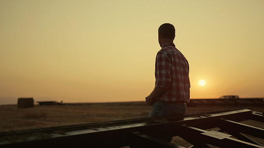 在金色的夕阳下农民检查麦田的收获情况视频的预览图