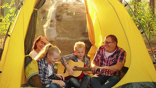 快乐的旅游家庭在阳光明媚的森林露营帐篷里快乐而友好地玩耍视频的预览图