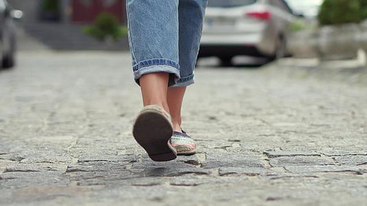 穿着牛仔裤和便鞋走在街上的女人的腿视频的预览图