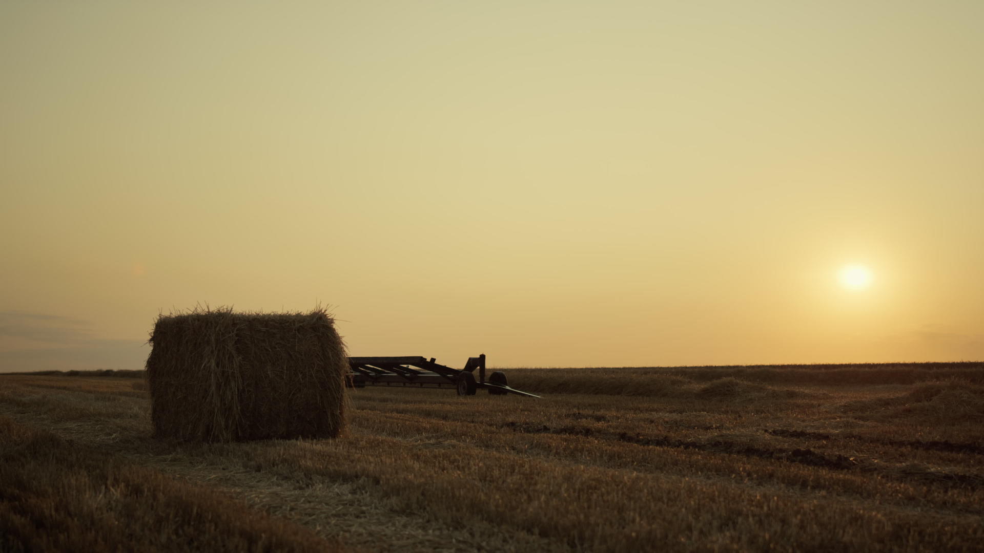 用收割设备在金色夕阳下的麦田上捆干草视频的预览图
