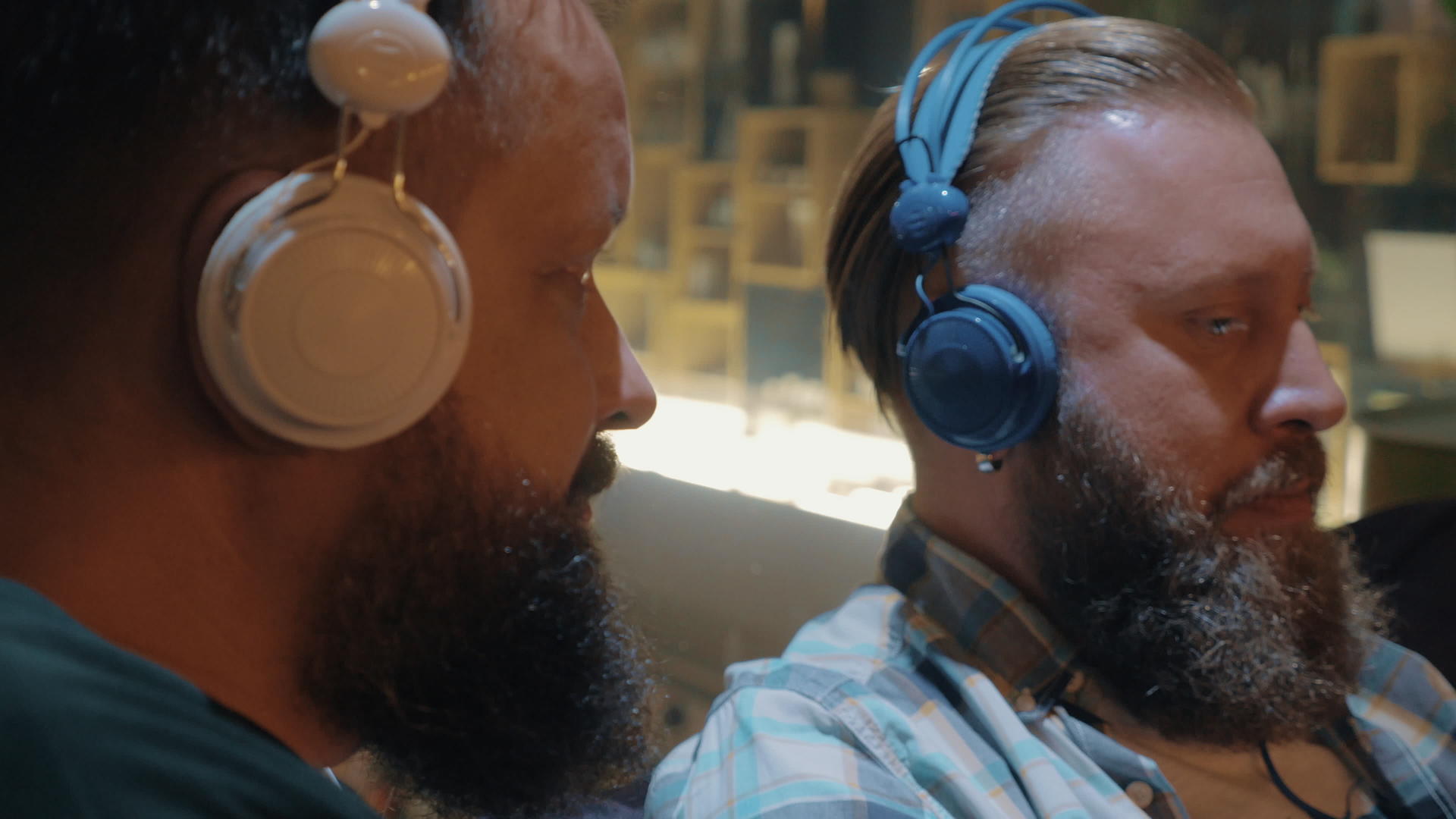 两个留胡子的男人用五颜六色的耳机听音乐视频的预览图