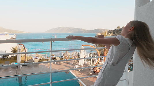 快乐的女孩拿着扶手在阳台度假酒店度假视频的预览图