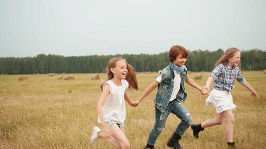快乐的年轻朋友手牵手在村里的收割场上奔跑视频的预览图