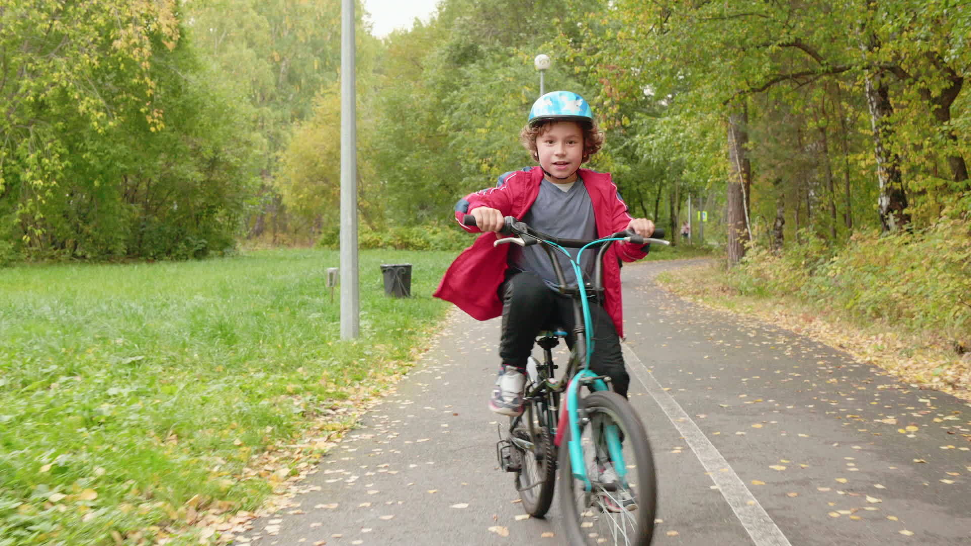 秋天在公园里骑自行车的快乐男孩视频的预览图