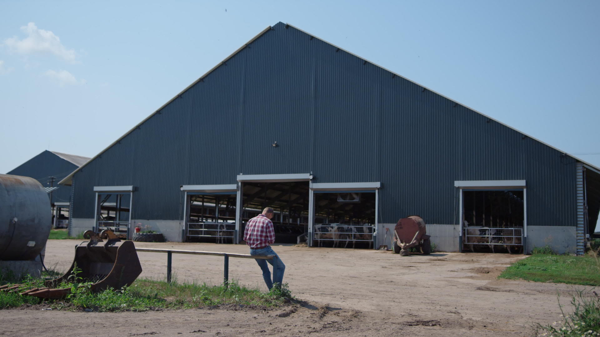 饲养牲畜后牧场工人坐在大牛棚外的栅栏上视频的预览图