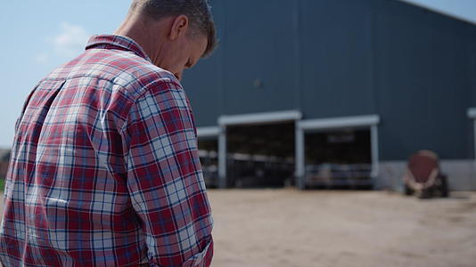 农民坐在农业综合院子里在畜牧设施特写工作后休息视频的预览图