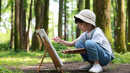 男孩在树林里画画视频的预览图