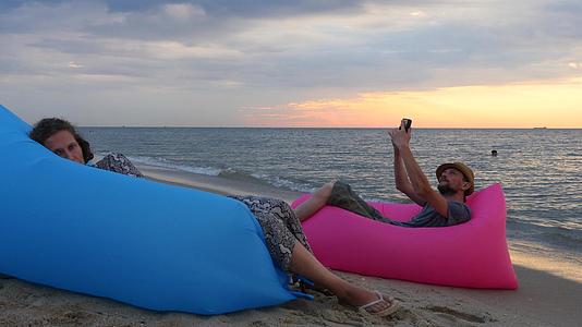 一对夫妇日出时坐在海滩上的气垫床上男人和女人在度假视频的预览图