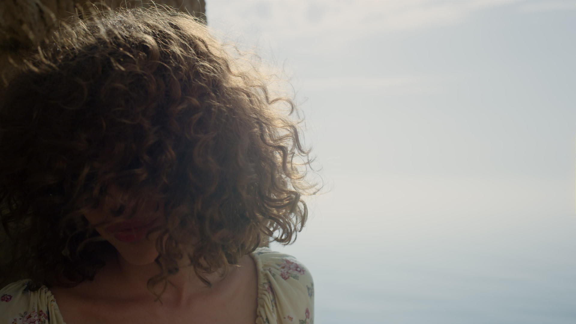 画像卷曲的女孩坐在沙滩上在阳光明媚的日子里摇着头发戴着太阳镜视频的预览图