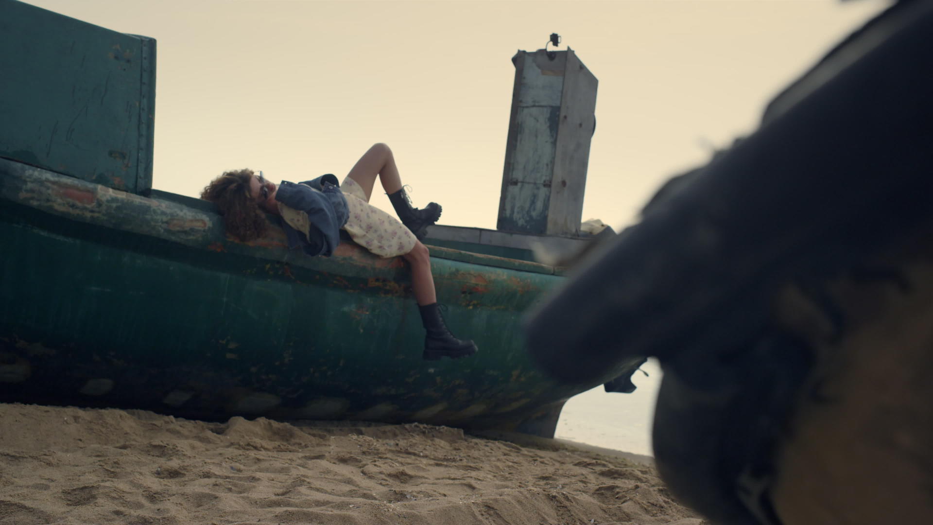 无忧无虑的女人躺在沙滩上的旧船上视频的预览图