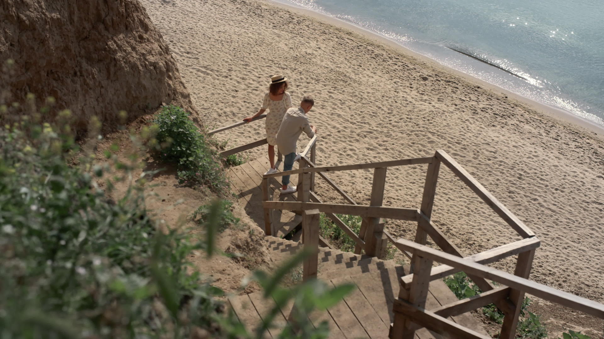无忧无虑的情侣游客站在空旷的海岸阳光明媚的早晨木梯上视频的预览图