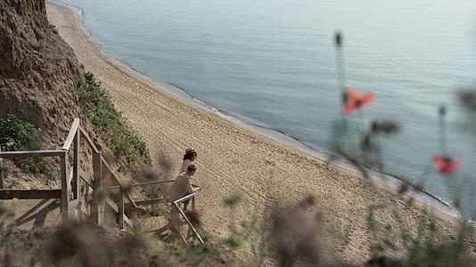 放松的夫妇们站在远处的沙滩楼梯上看海景视频的预览图