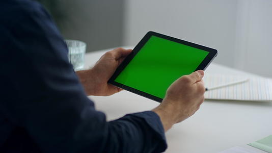 商人手里拿着一台绿屏平板电脑视频的预览图