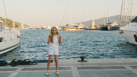 性格开朗的女孩在港口和游艇的码头上快乐地跳舞视频的预览图