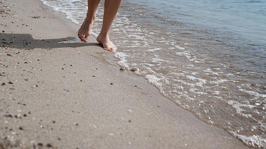 特写女性腿在海浪附近行走湿沙视频的预览图
