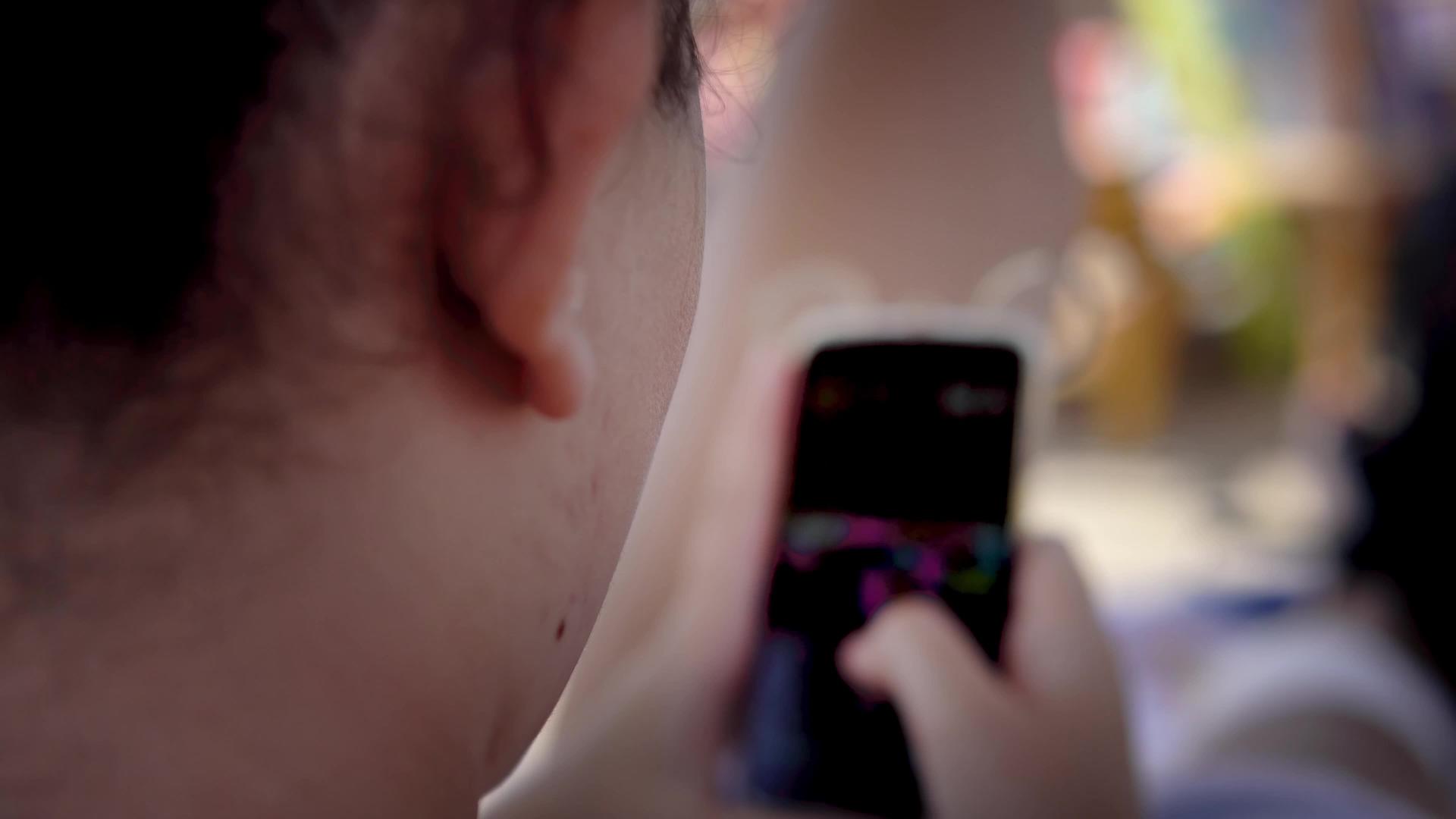 快乐的女孩在暑假期间玩智能手机游戏非常开心视频的预览图