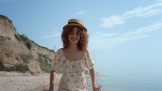 可爱的卷发女孩拿着裙子在海浪上跳舞视频的预览图