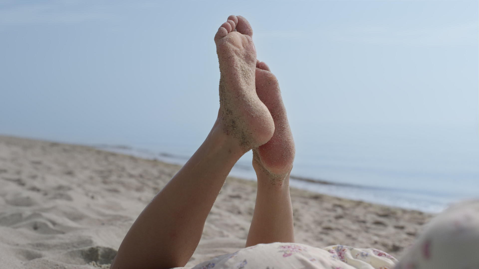 可爱的女孩在沙滩上举起双腿躺在沙滩上夏天视频的预览图