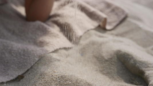 微笑的女人在夏天躺在沙滩上的手指间倒沙视频的预览图